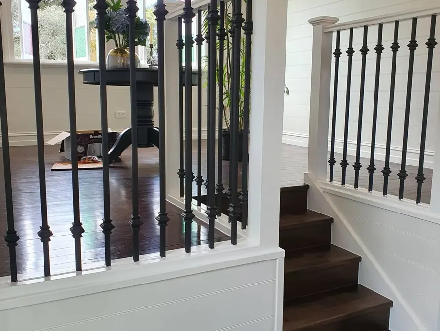 A white panelled stair with black balusters and dark timber treads